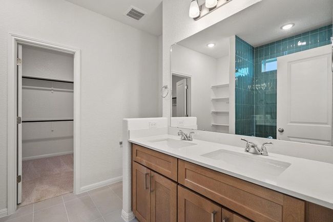 Bathroom with a walk in closet, double vanity, tile patterned floors, and tiled shower | Image 18