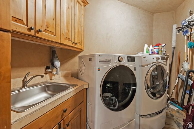 Laundry area featuring washing machine and clothes dryer, a sink, and cabinet space | Image 56