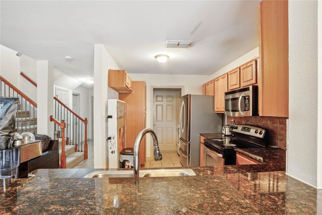 Kitchen with appliances with stainless steel finishes, dark stone countertops, tasteful backsplash, and open floor plan | Image 11