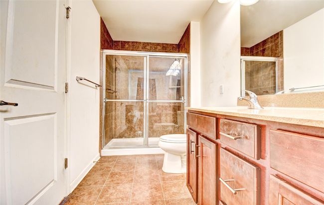 Full bathroom featuring a stall shower, toilet, vanity, and tile flooring | Image 18