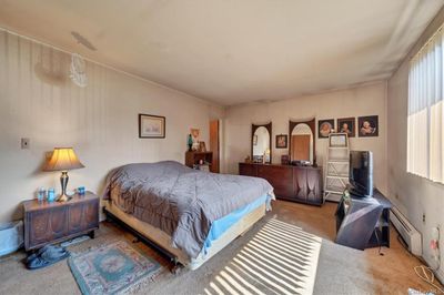 Carpeted bedroom with multiple windows and a baseboard heating unit | Image 3