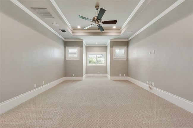 Spare room with ceiling fan, light carpet, a tray ceiling, and visible vents | Image 32