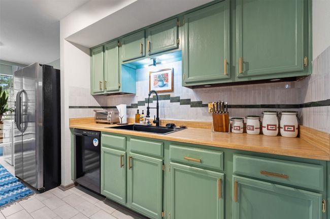 Kitchen with a sink, stainless steel fridge with ice dispenser, light countertops, black dishwasher, and backsplash | Image 20
