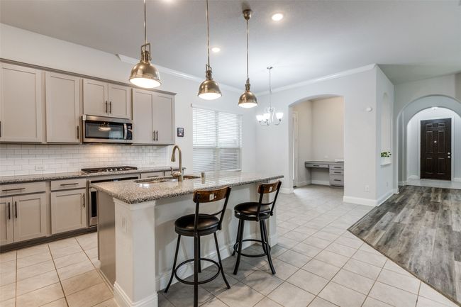 Kitchen featuring tasteful backsplash, light tile patterned floors, appliances with stainless steel finishes, arched walkways, and a sink | Image 12