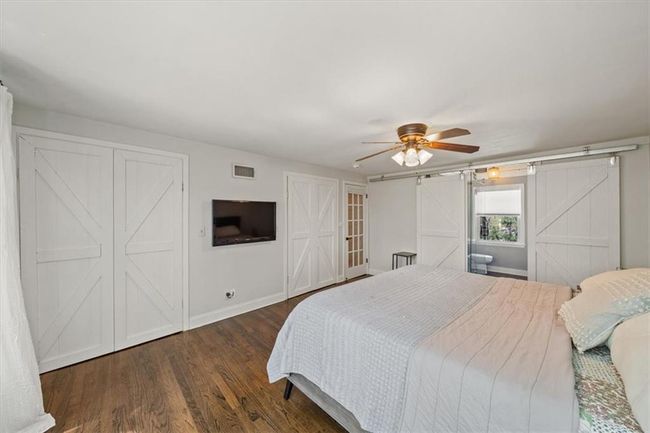 Primary Bedroom with wood finished floors, a barn door, ceiling fan, baseboards, and visible vents | Image 16