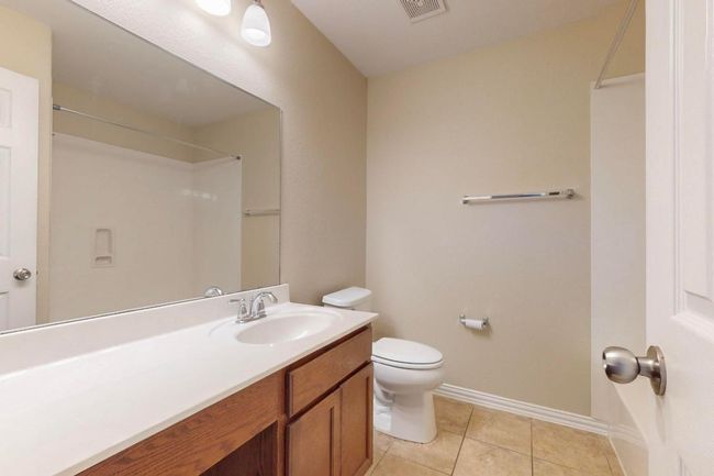 Full bathroom featuring vanity, visible vents, toilet, tile patterned floors, and baseboards. Linen closet behind the door. New light fixture just installed. | Image 24