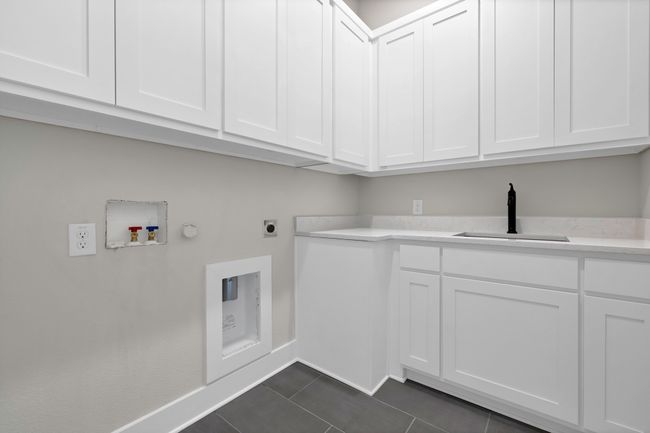 Laundry area featuring cabinet space, hookup for an electric dryer, washer hookup, dark tile patterned flooring, and hookup for a gas dryer | Image 35