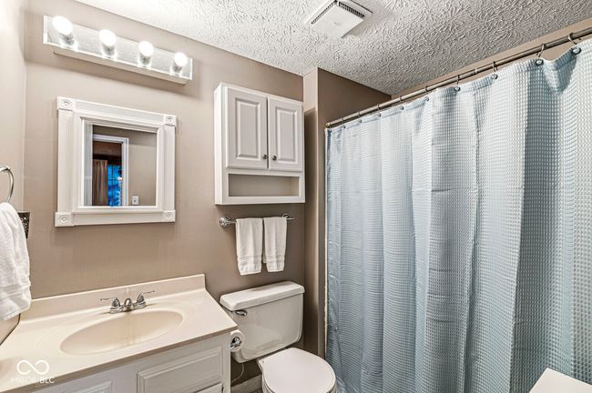 full bathroom featuring vanity, a textured ceiling, and a shower with shower curtain | Image 14