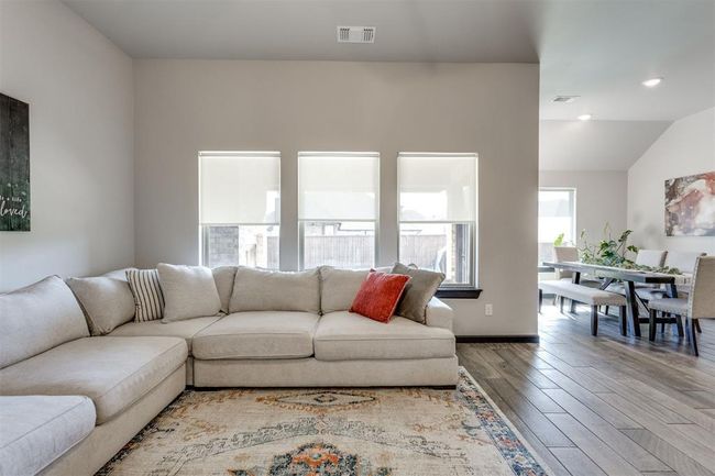 Living area featuring vaulted ceiling, baseboards, wood finished floors, and visible vents | Image 40