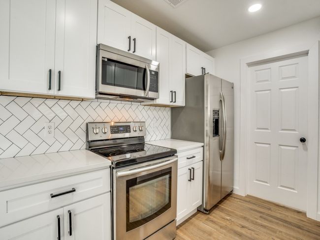 Kitchen featuring appliances with stainless steel finishes, light countertops, white cabinetry, and recessed lighting | Image 6