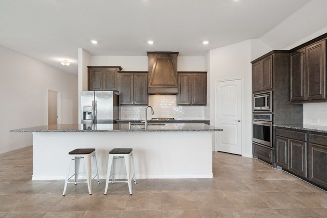 Kitchen with appliances with stainless steel finishes, custom exhaust hood, an island with sink, decorative backsplash, and recessed lighting | Image 10
