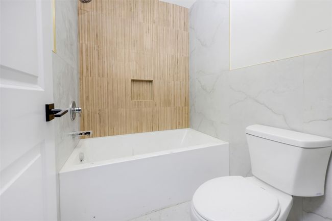 Bathroom featuring toilet, tub / shower combination, and tile walls | Image 34