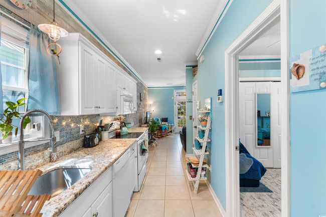 Kitchen with a sink, white appliances, crown molding, white cabinetry, and tasteful backsplash | Image 12