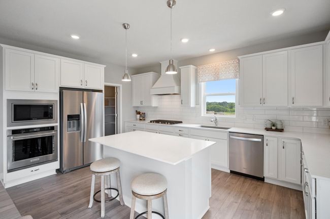 Gourmet kitchen appliances featuring a 5-burner gas cooktop, vented hood, wall microwave and oven and dishwasher. Model photo. Options and colors will vary. | Image 4