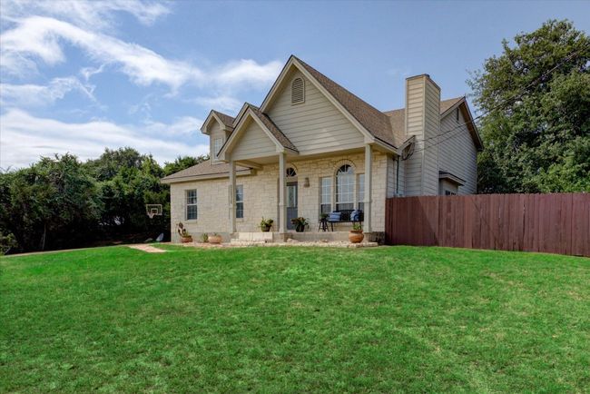 Front of the house features a covered porch and xeriscaped planting area. Fenced yard on the right side of the house. | Image 4