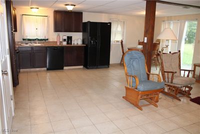 Kitchen featuring black appliances, light stone counters, dark brown cabinetry, and sink | Image 3