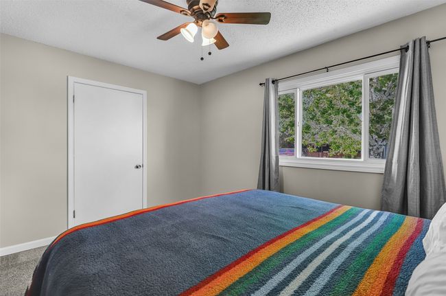 Bedroom with carpet flooring, a textured ceiling, ceiling fan, and baseboards | Image 20