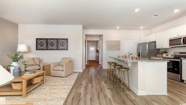 Kitchen with stainless steel appliances, light stone countertops, light wood-style flooring, and a kitchen bar | Image 8