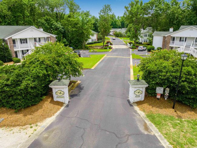 View of asphalt street featuring a residential view, street lights, view of scattered trees, and curbs | Image 4