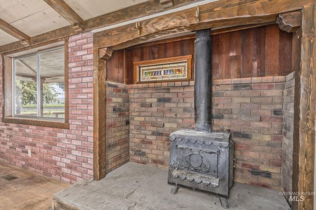 Detailed view of a wood stove, beam ceiling, and brick wall | Image 6