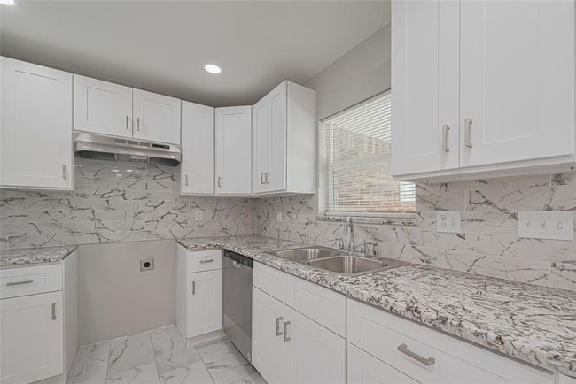 Coordinated gray and white tones blend across the backsplash and countertops, creating a sleek and modern kitchen atmosphere. | Image 10