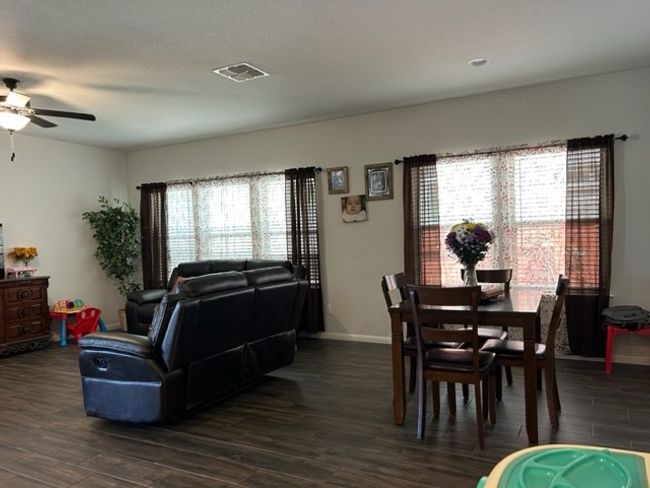 Living room featuring ceiling fan, visible vents, baseboards, and dark wood-type flooring | Image 6