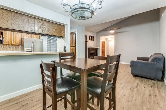 Dining area with lofted ceiling, light wood finished floors, a fireplace, a chandelier, and a ceiling fan | Image 14