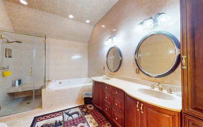 Bathroom with tile walls, a bath, double vanity, and a stall shower | Image 45