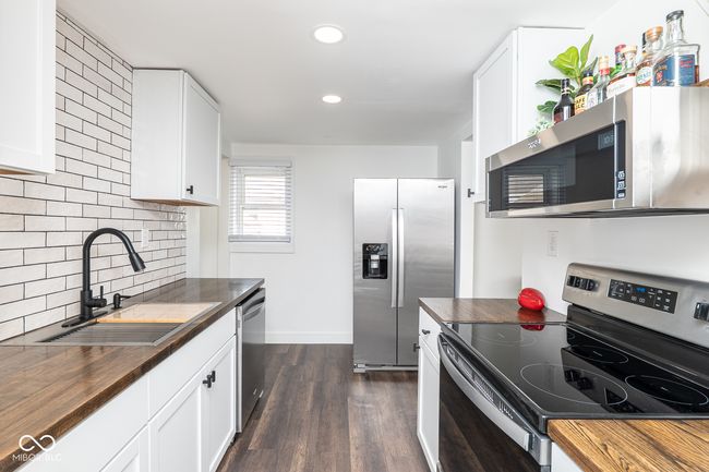 kitchen with a sink, butcher block countertops, appliances with stainless steel finishes, and dark wood finished floors | Image 10