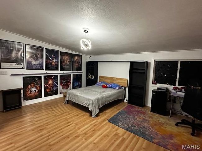 Bedroom featuring vaulted ceiling, hardwood / wood-style flooring, and a textured ceiling | Image 7