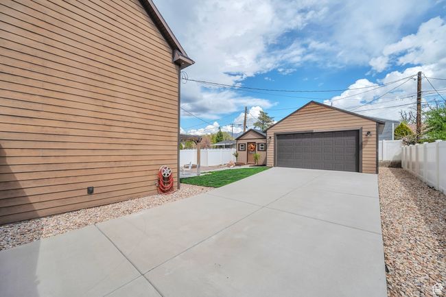 View of home's exterior featuring a garage, fence, and an outdoor structure | Image 24