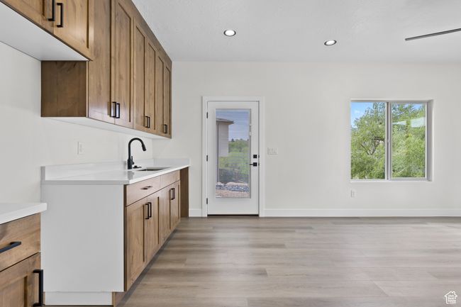 Kitchen featuring light countertops, recessed lighting, baseboards, a sink, and light wood-style floors | Image 15
