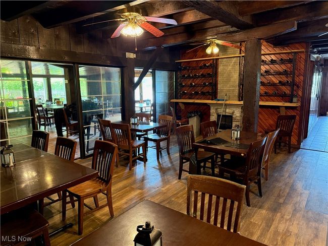 Dining area featuring a ceiling fan, wooden walls, wood finished floors, and beam ceiling | Image 25