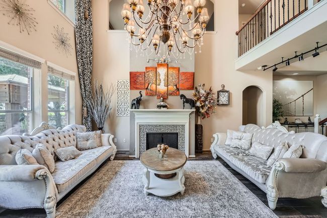 Living room with a high ceiling, a chandelier, and a fireplace | Image 7