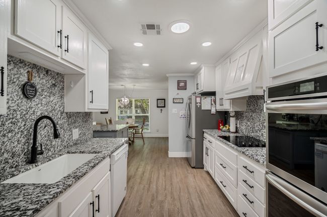 Kitchen featuring appliances with stainless steel finishes, recessed lighting, tasteful backsplash, and white cabinetry | Image 7