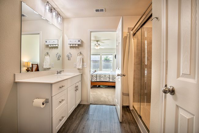 Full bath featuring connected bathroom, a shower stall, wood finished floors, vanity, and ceiling fan | Image 15