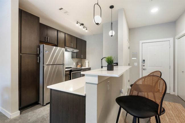 The kitchen boasts quartz countertops and stainless steel appliances | Image 8