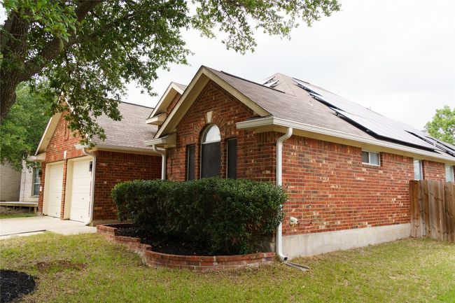 View of side of home with brick siding, driveway, roof mounted solar panels, and a garage | Image 31