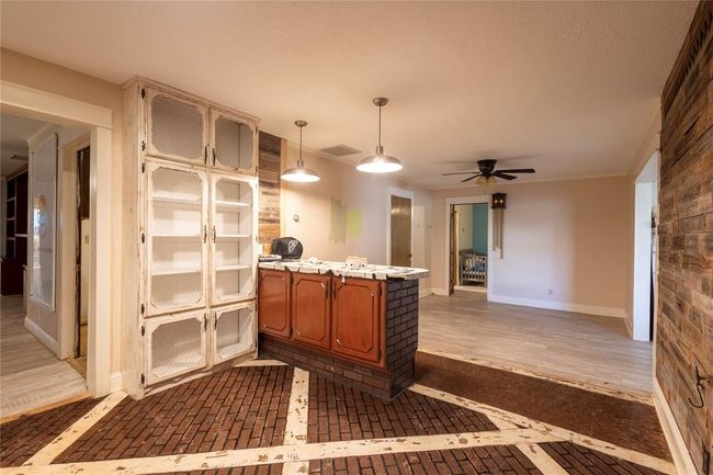 Kitchen featuring brown cabinetry, a ceiling fan, light countertops, a peninsula, and inlaid floor details | Image 4