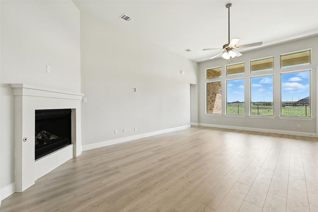 Unfurnished living room featuring a ceiling fan, light wood finished floors, and a fireplace | Image 10