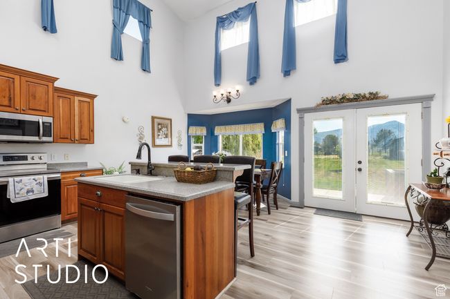 Kitchen with appliances with stainless steel finishes, a sink, high vaulted ceiling, brown cabinets, and french doors | Image 10