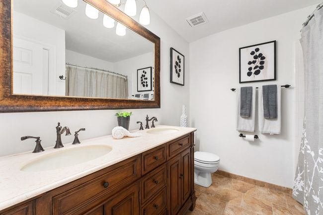 Full bathroom with double vanity, stone finish floors, and curtained shower | Image 20