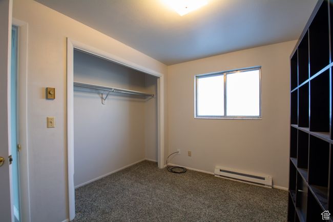 Unfurnished bedroom with carpet, a closet, and a baseboard heating unit | Image 7