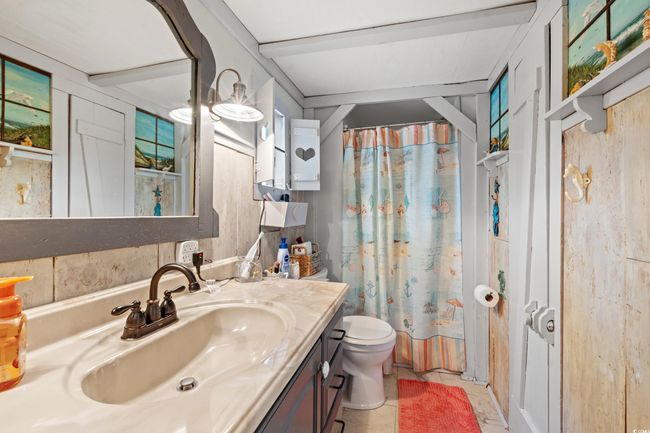 Full bathroom with vanity, tile patterned floors, wooden walls, toilet, and shower / tub combo | Image 19