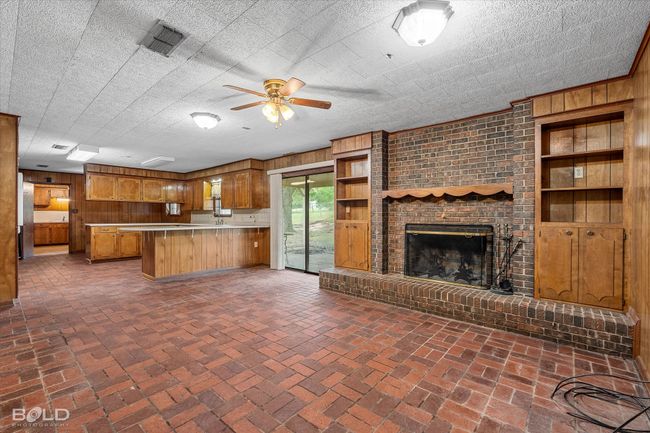 Kitchen with wooden walls, a ceiling fan, open floor plan, a peninsula, and brown cabinets | Image 11