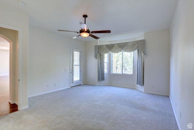 Spare room with arched walkways, carpet flooring, ceiling fan, and baseboards | Image 11