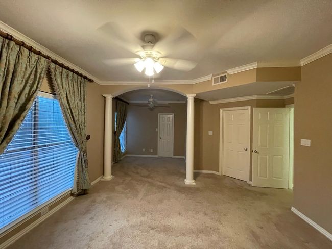 Unfurnished room with ceiling fan, decorative columns, carpet, arched walkways, and crown molding | Image 12