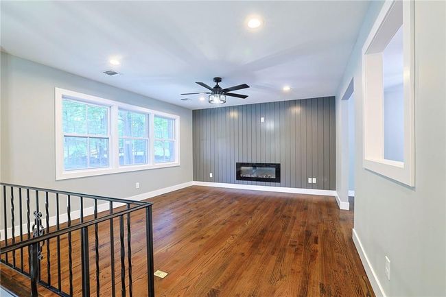 Unfurnished living room featuring ceiling fan, a large fireplace, and hardwood / wood-style flooring | Image 5