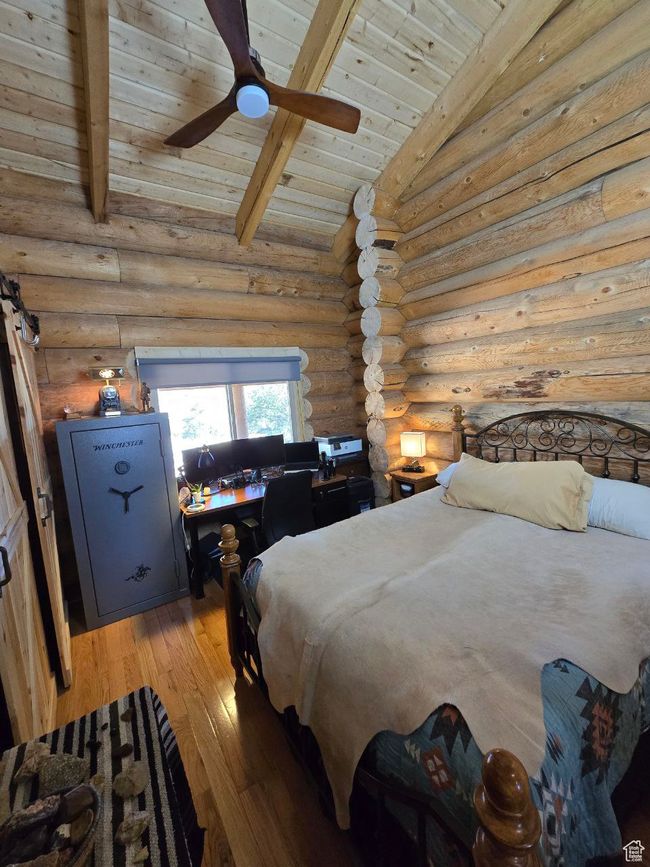 Bedroom with light wood-style flooring, a ceiling fan, log walls, wood ceiling, and vaulted ceiling with beams | Image 72