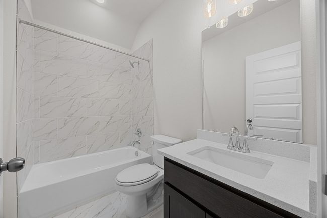 Bathroom featuring toilet, vanity, shower combination, and marble look tile flooring | Image 26
